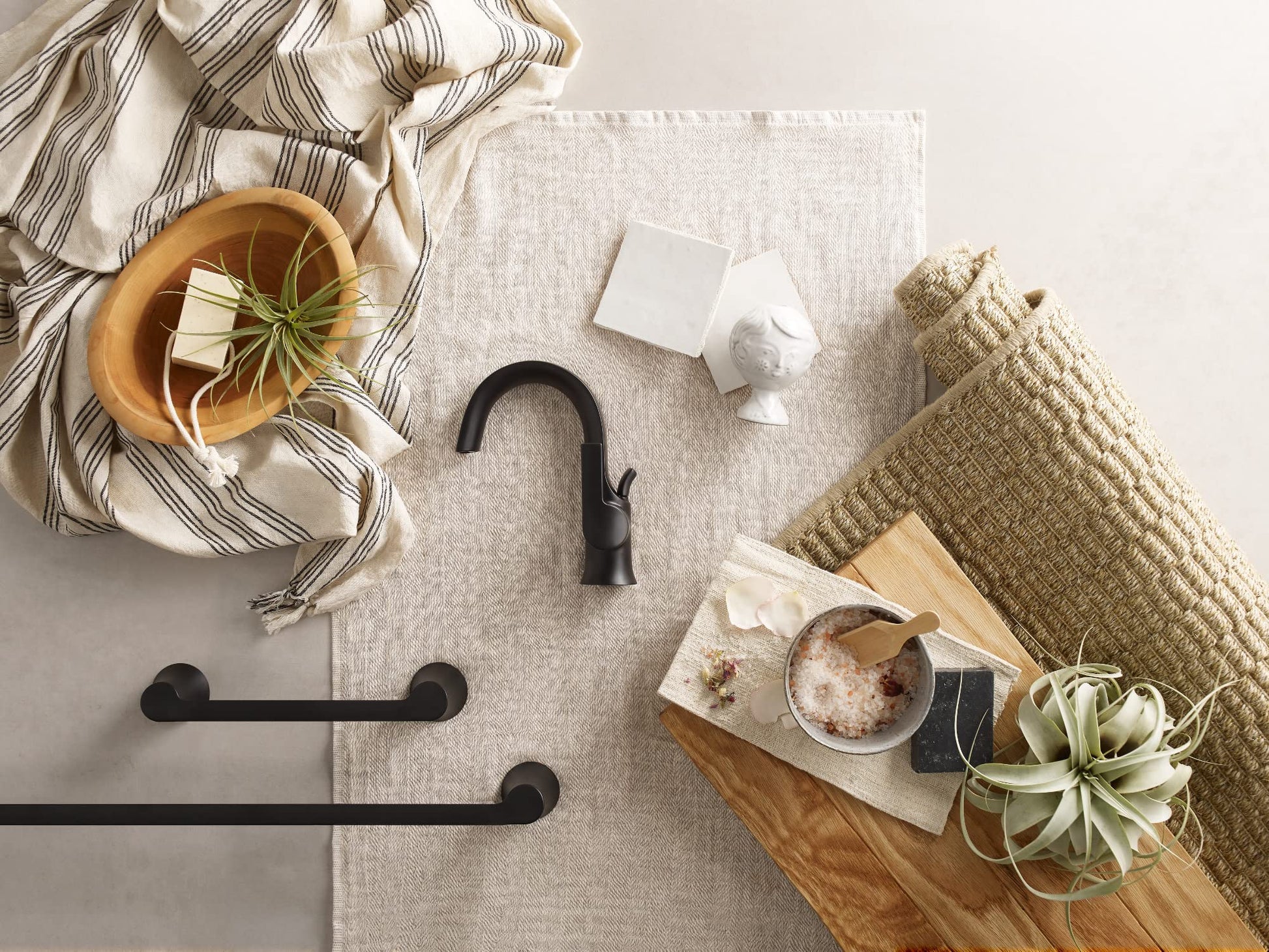 Matte black single-handle bathroom faucet with curved spout displayed on neutral fabric with decorative items.