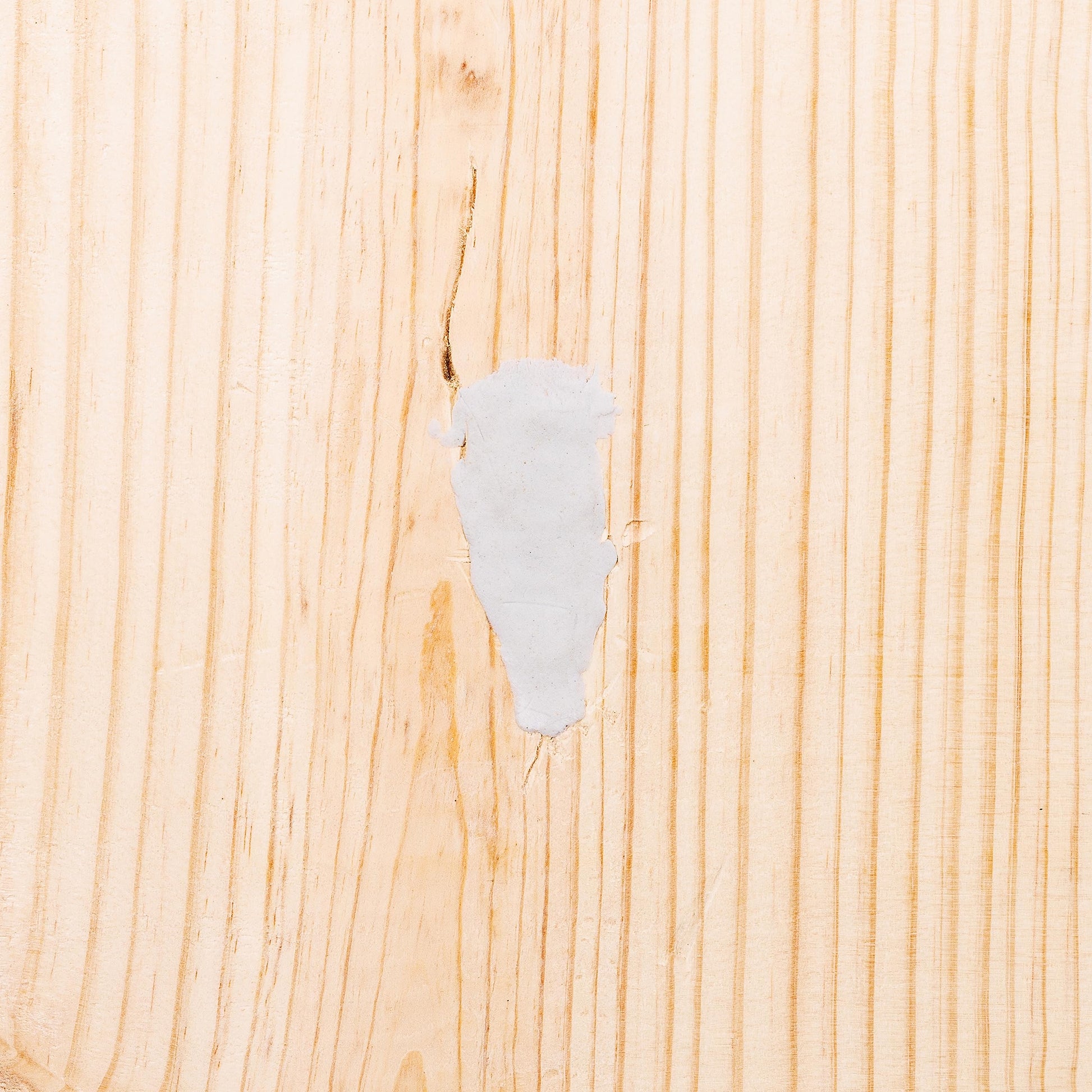 Gray epoxy repair putty applied to wood surface showing coverage and texture.