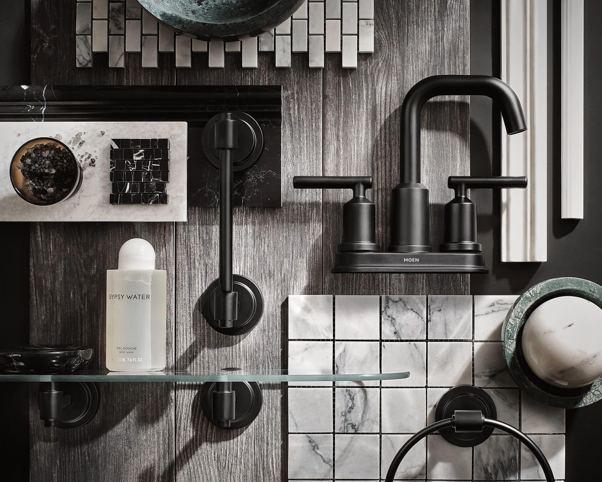 Matte black two-handle centerset bathroom faucet with curved spout and cylindrical handles mounted above marble tile sink.