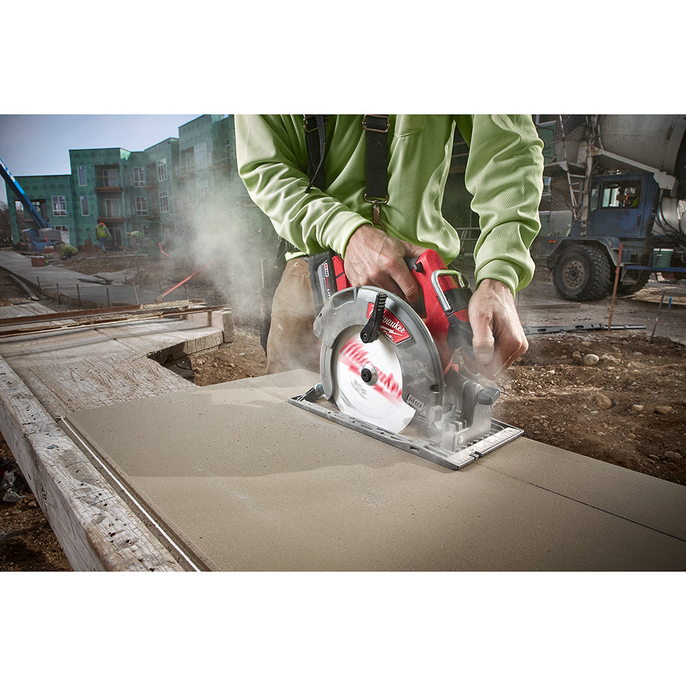 Milwaukee circular saw with red and gray housing cutting through fiber cement board on a construction site, creating dust.