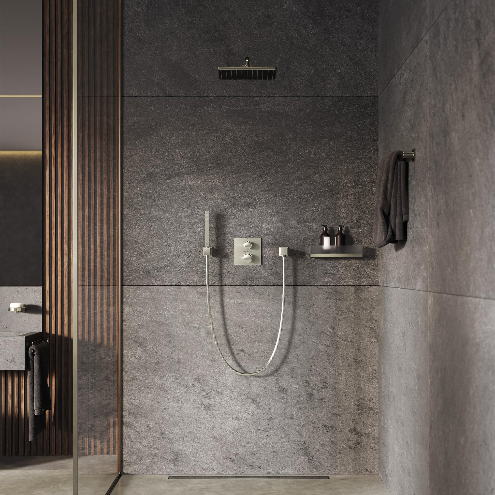 Brushed metal dual-handle thermostatic shower valve trim mounted on gray tile wall with handheld spray and overhead showerhea
