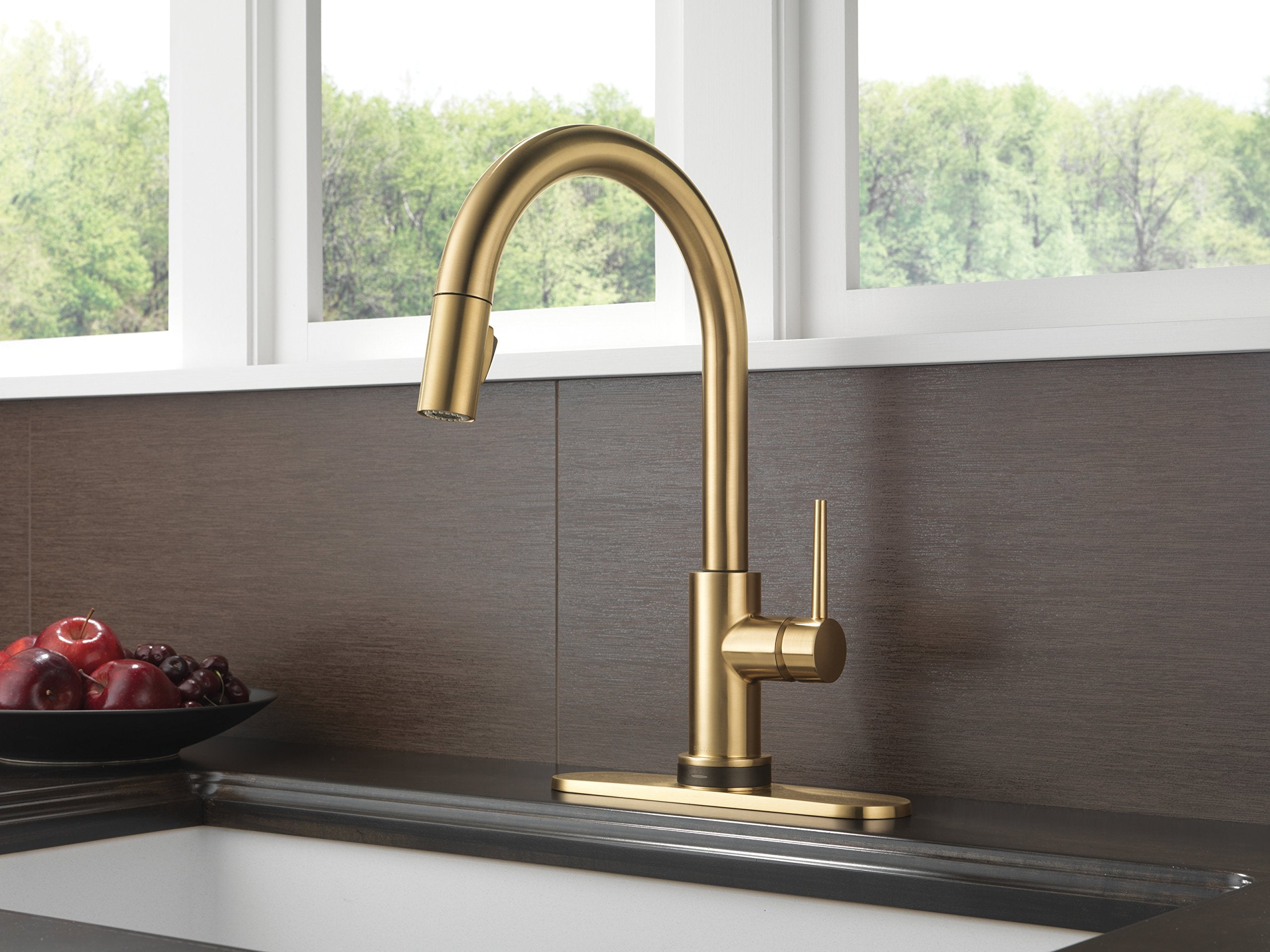 Champagne bronze kitchen faucet with curved spout and single lever handle mounted on sink deck.