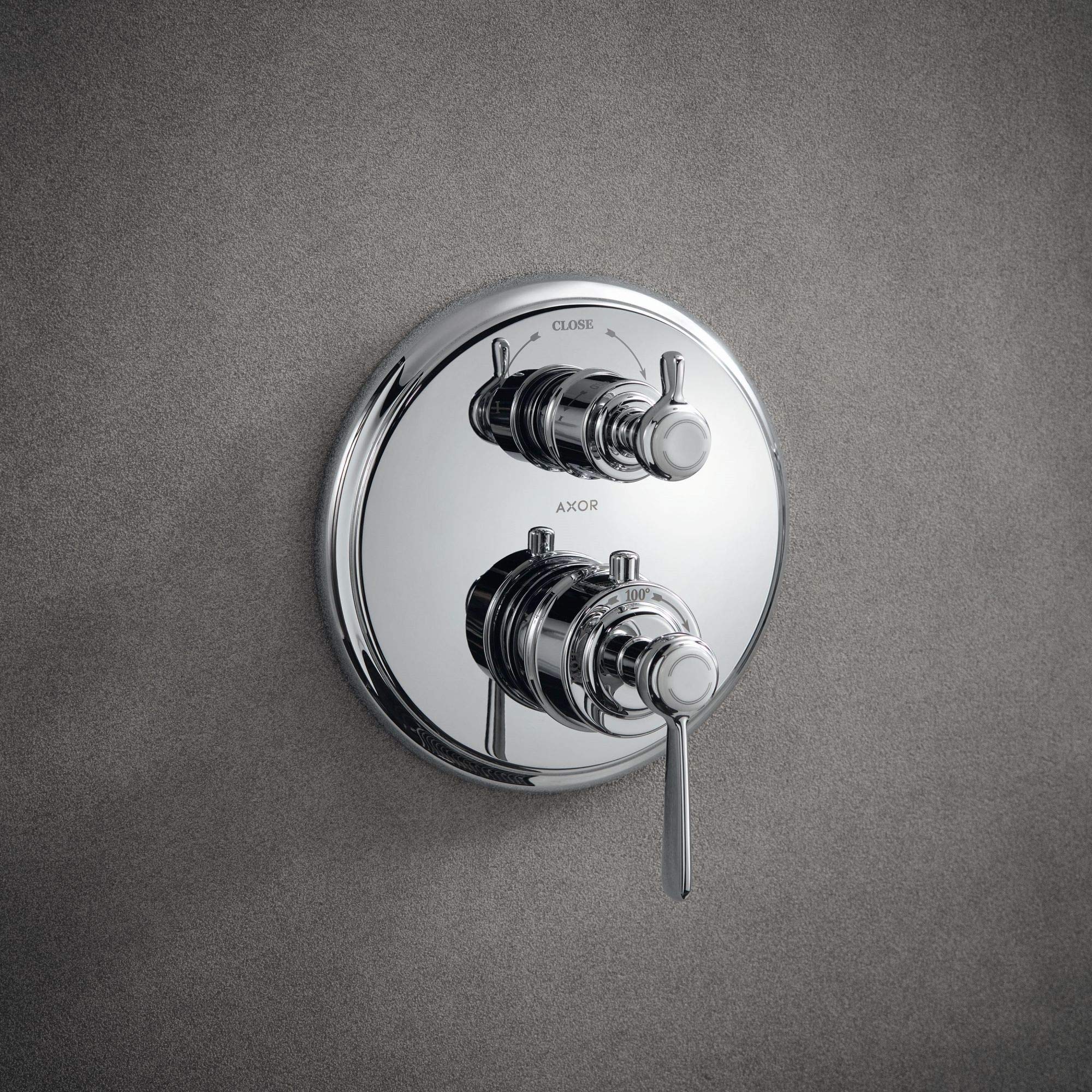 Polished nickel thermostatic shower trim with dual handles, diverter valve, and circular trim ring mounted on gray wall.