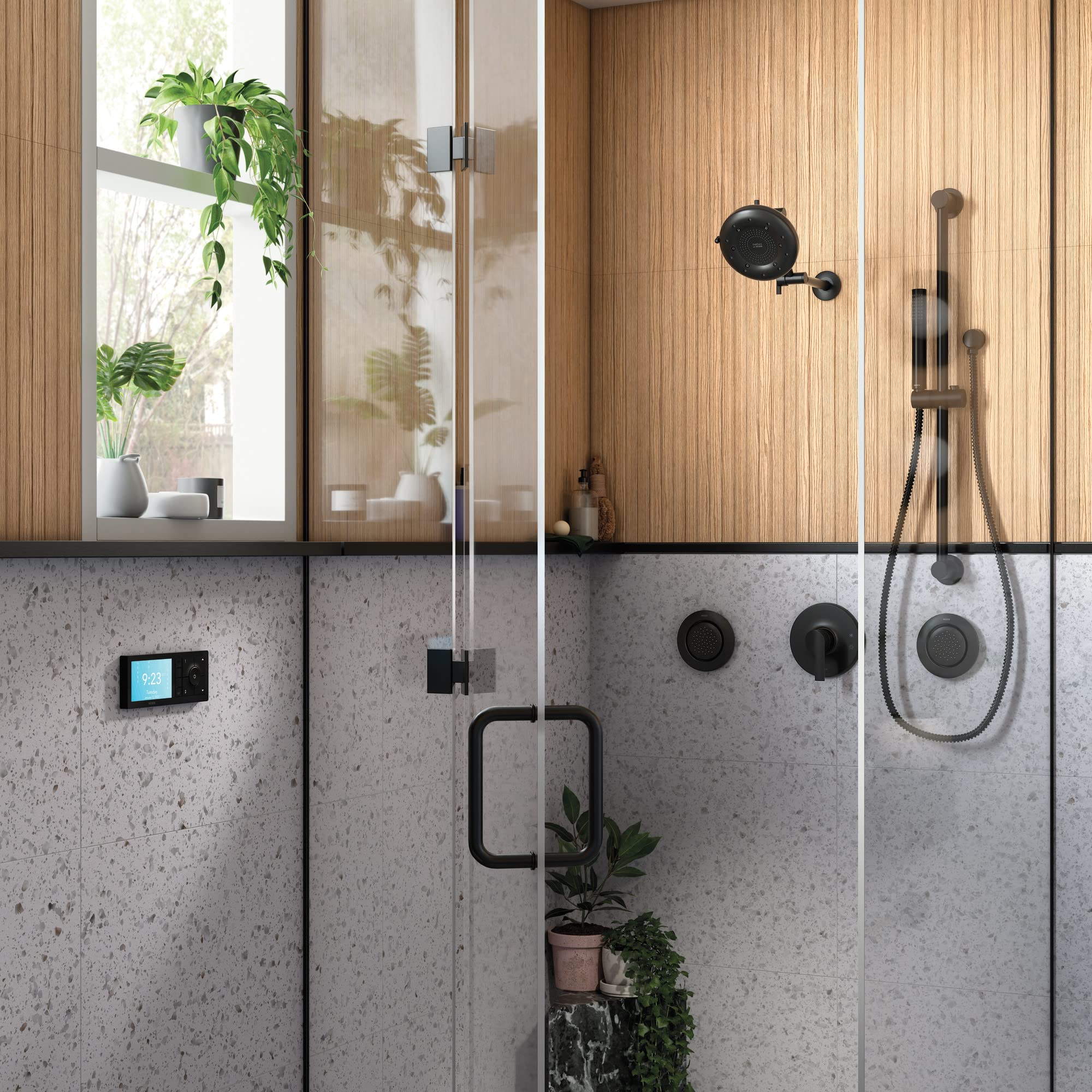 Matte black shower trim kit with single handle, showerhead, and handheld spray mounted on concrete tile wall.