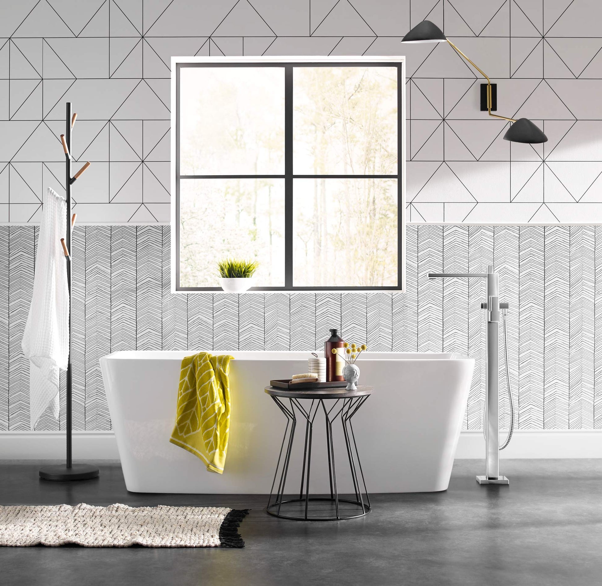 Chrome floor-mounted tub filler with single handle and matching handheld showerhead next to white freestanding bathtub.