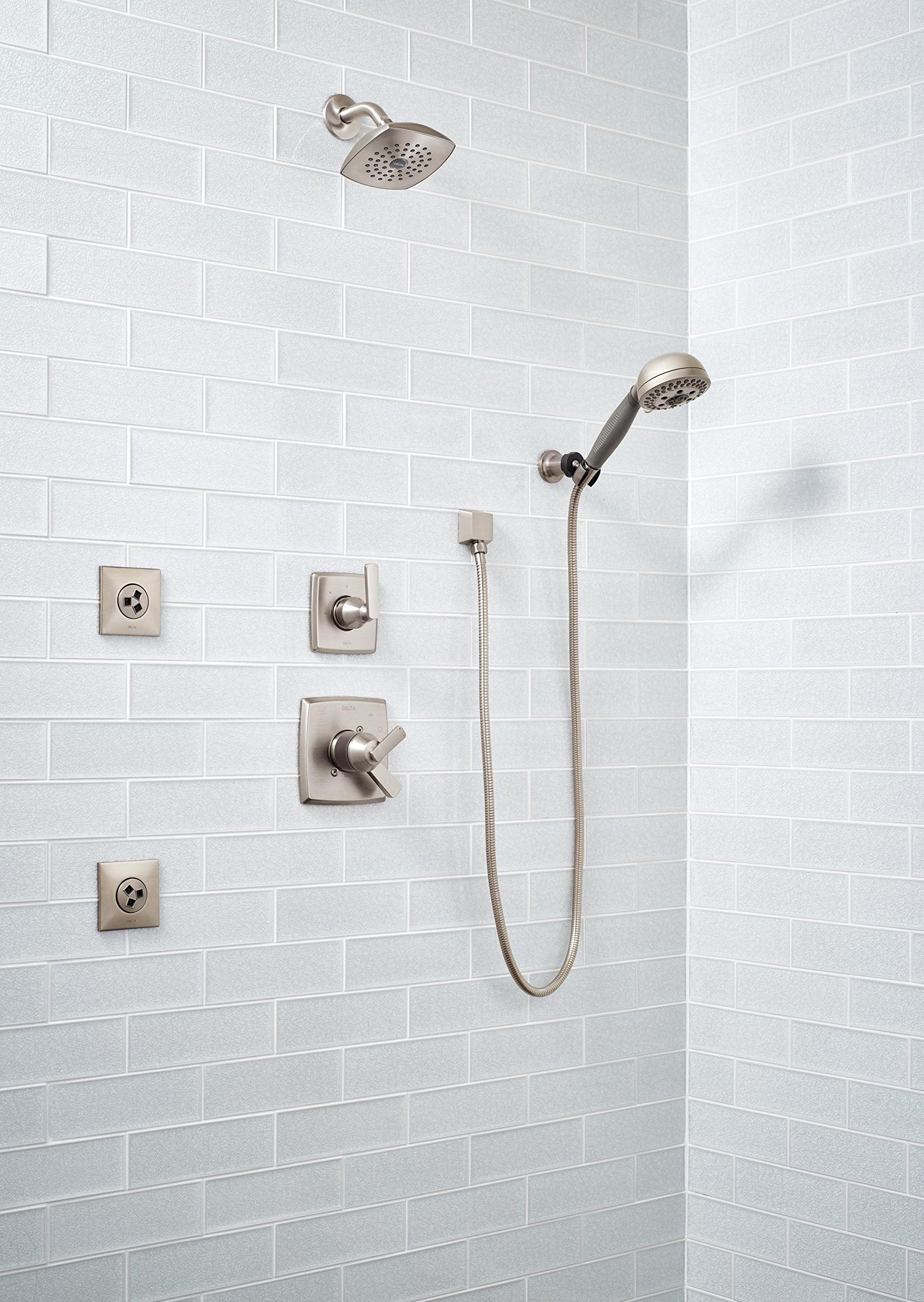 Stainless steel square wall elbow connector mounted on white subway tile, connecting hand shower hose to wall outlet.