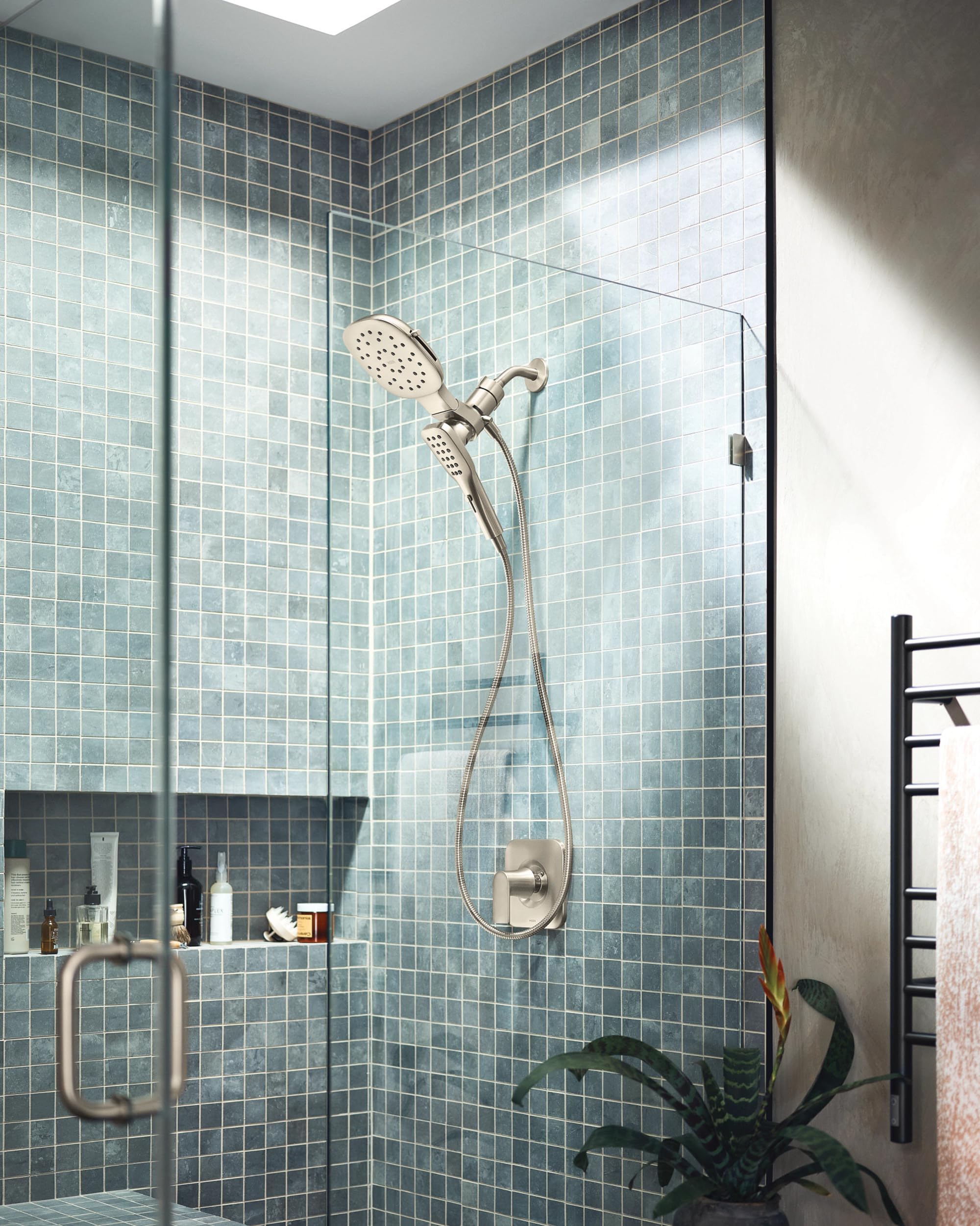 Brushed nickel shower system with square rainfall head and detachable hand shower mounted on tiled bathroom wall.