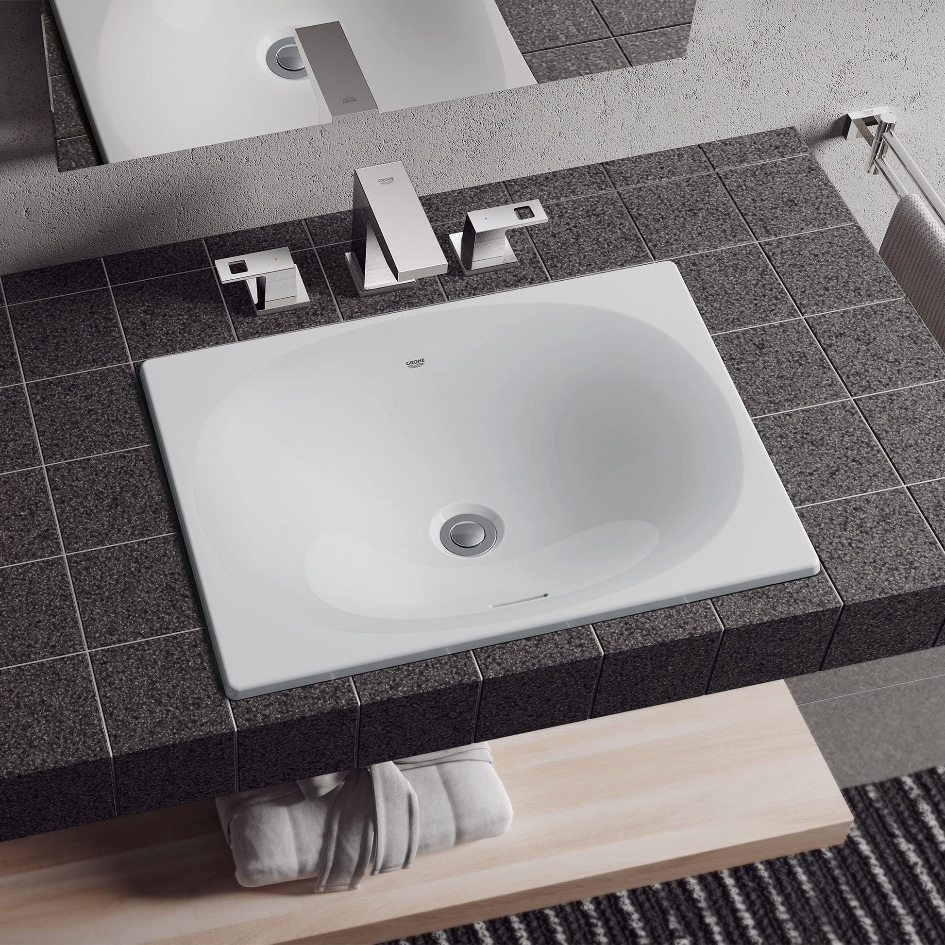 White square under-counter bathroom sink installed in dark gray tile countertop with chrome faucet and fixtures.