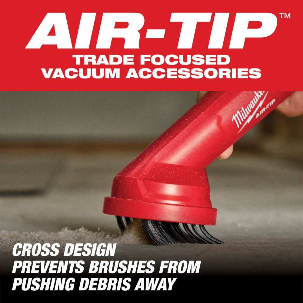 Red Milwaukee AIR-TIP vacuum brush attachment with cross-pattern bristles held against concrete surface.