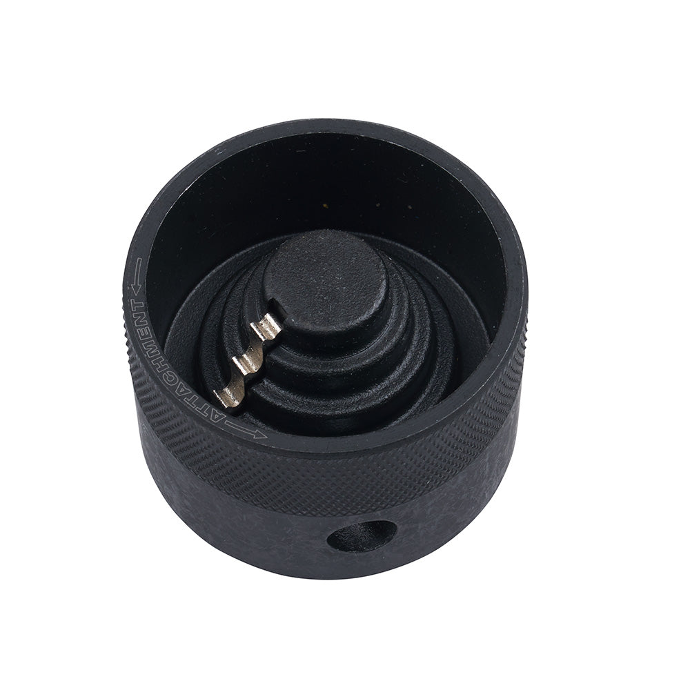 Black cylindrical reamer attachment with concentric cutting blades and metal pins inside, viewed from above.