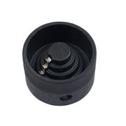 Black cylindrical reamer attachment with concentric cutting blades and metal pins inside, viewed from above.