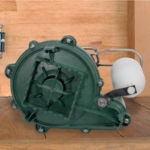 Cast iron submersible sump pump with green housing and white electrical connector on wooden surface.