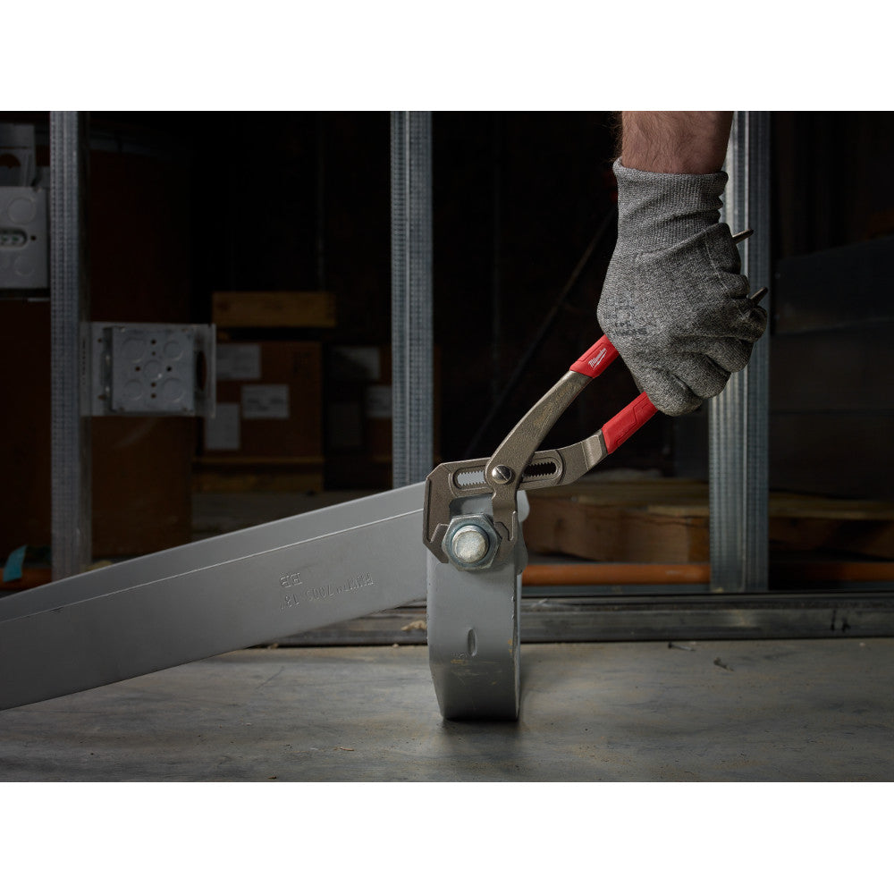 Milwaukee hex-jaw pliers with red and tan handle gripping a metal pipe on a work surface.