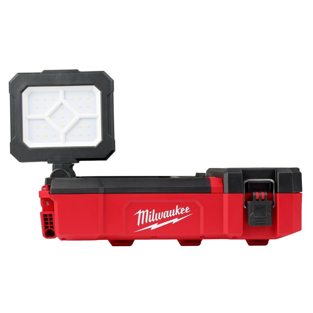 Black and red Milwaukee M12 PACKOUT flood light with white LED panel mounted on red storage base.