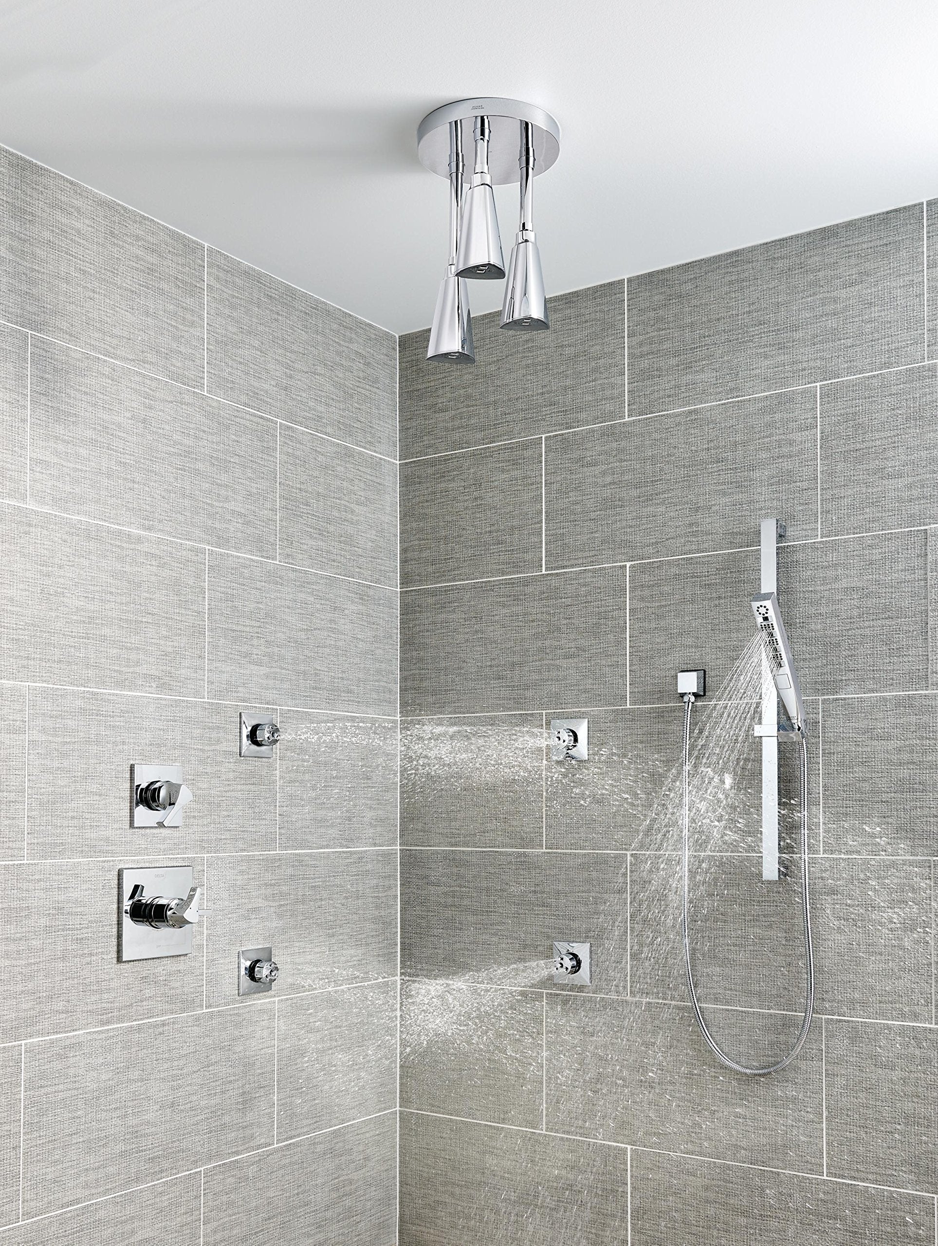 Chrome square wall elbow mounted to ceiling with hand shower hose attached in bathroom shower enclosure.