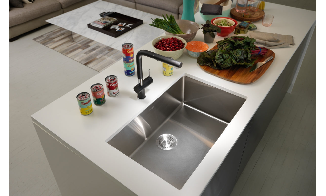 Rectangular stainless steel undermount sink with single bowl installed in white countertop, paired with black faucet.
