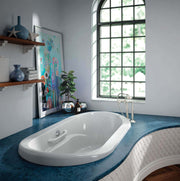 White oval drop-in bathtub with raised deck and seating in modern bathroom with blue countertop.