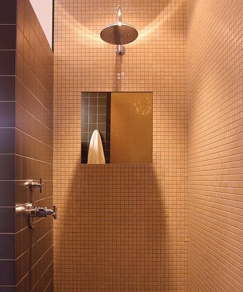 Rectangular fog-free mirror mounted in tiled shower enclosure with overhead rainfall showerhead and wall-mounted fixtures.