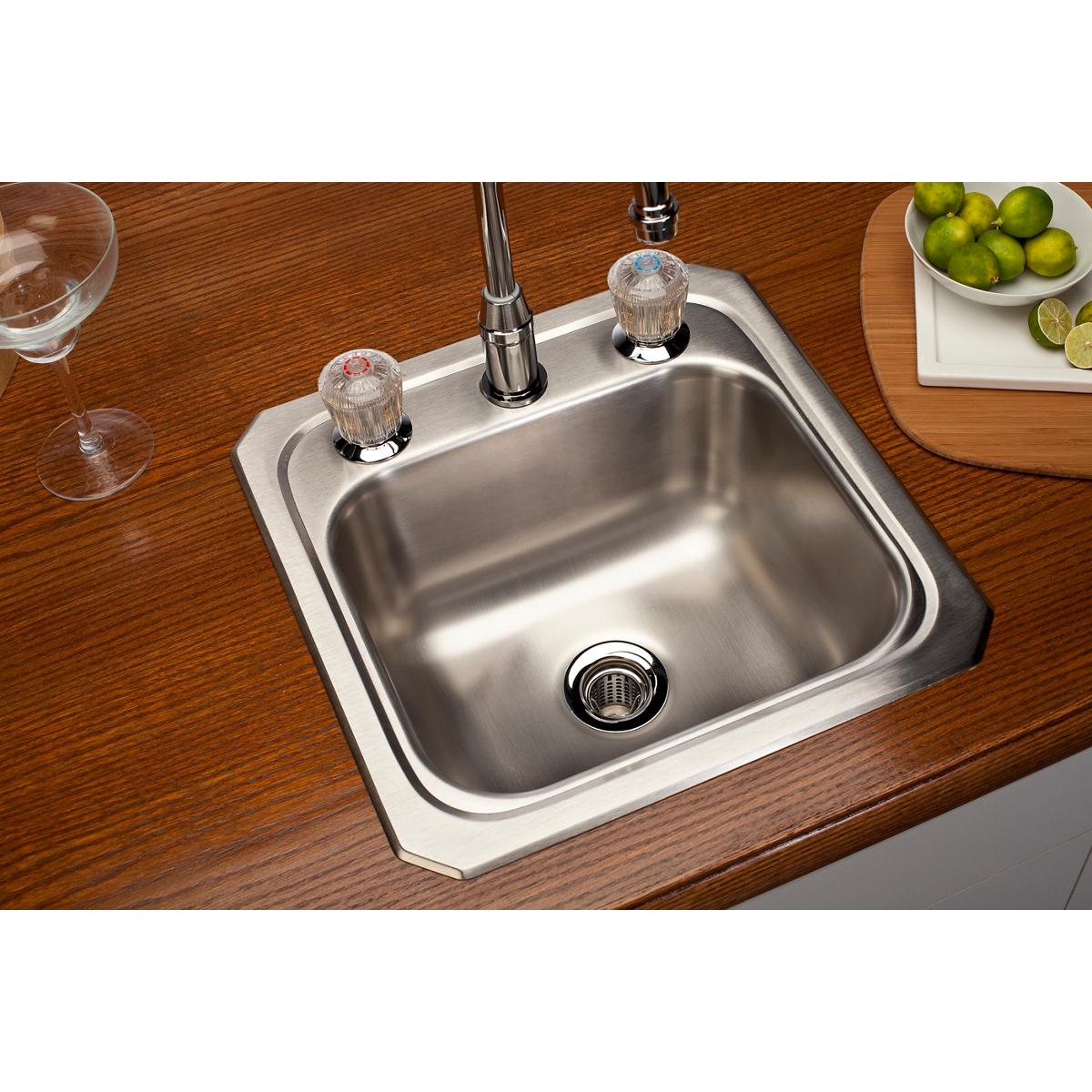 Stainless steel square bar sink with single bowl, chrome faucet, and drain strainer mounted in wooden countertop.