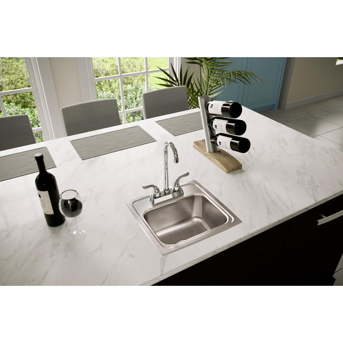 Stainless steel drop-in bar sink with single bowl and chrome faucet installed in white marble countertop.