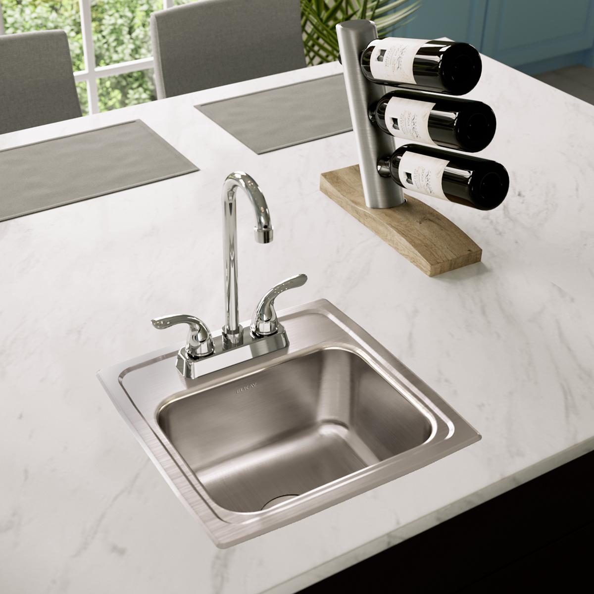 Stainless steel drop-in bar sink with single bowl, chrome faucet, and two drain holes installed in white countertop.
