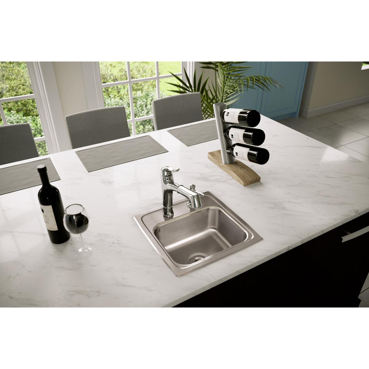 Stainless steel drop-in bar sink with single bowl and chrome faucet installed in marble countertop.