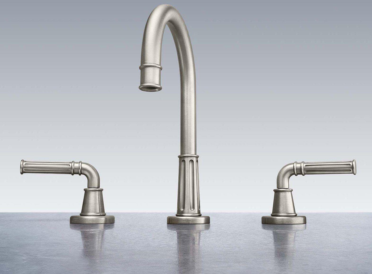 Satin brass three-piece widespread lavatory faucet with curved center spout and lever handles on left and right.