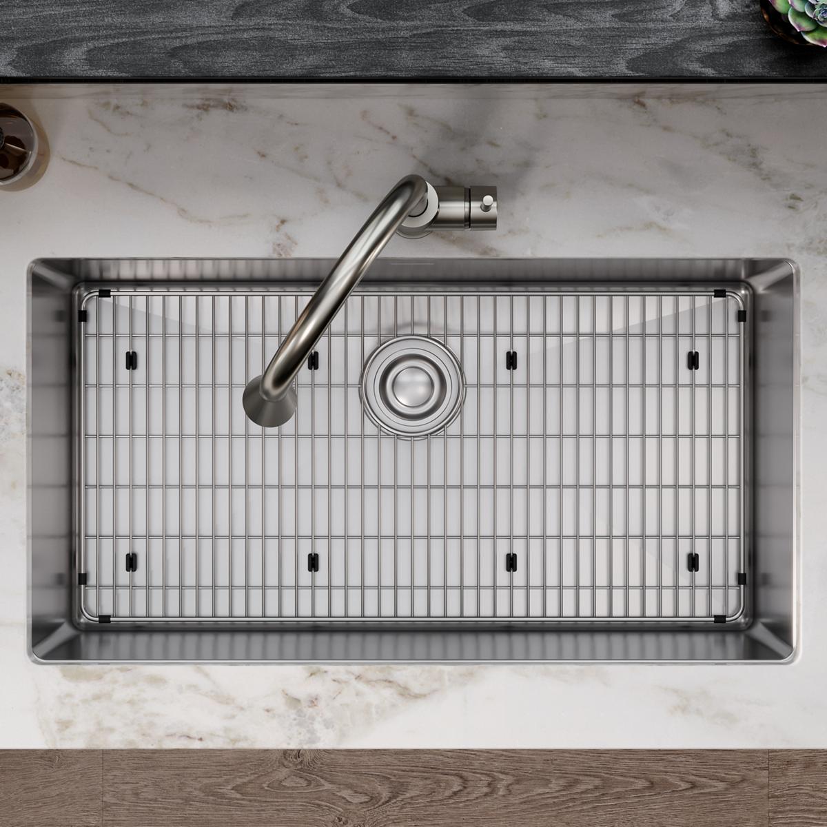 Stainless steel sink grid with vertical slat pattern and mounting feet, viewed from above in kitchen sink.