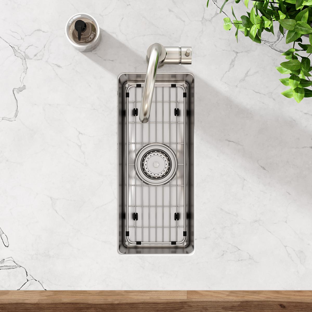 Stainless steel sink grid with vertical slats and a circular strainer opening, displayed in a rectangular sink basin.