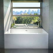 White rectangular soaking bathtub installed in alcove with large window overlooking cityscape and greenery.