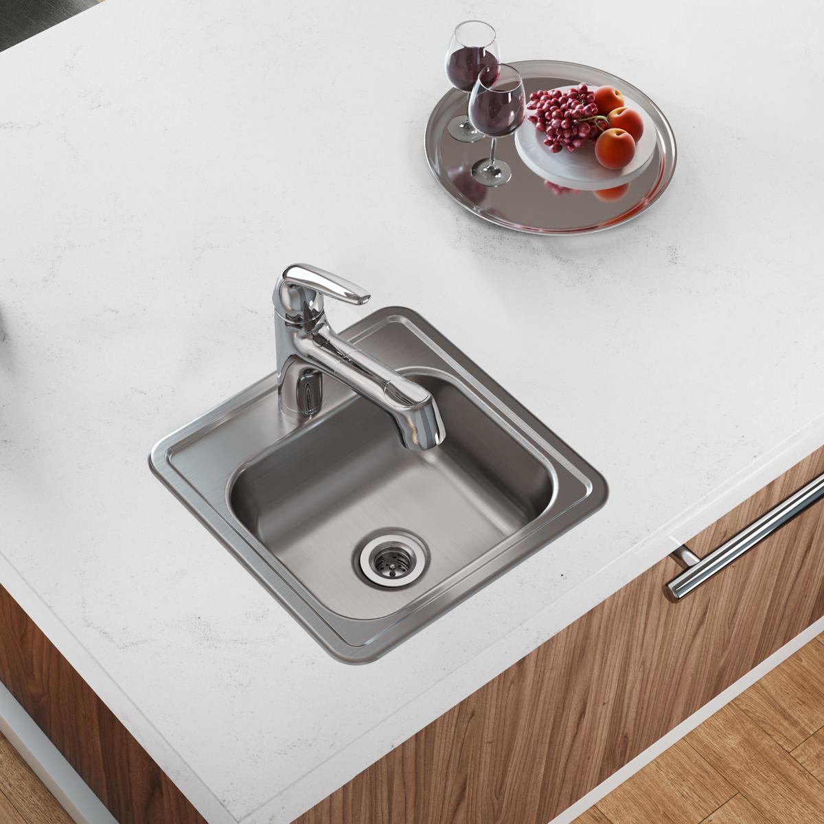 Stainless steel drop-in bar sink with single bowl, faucet, and drain installed in white countertop next to wood cabinetry.