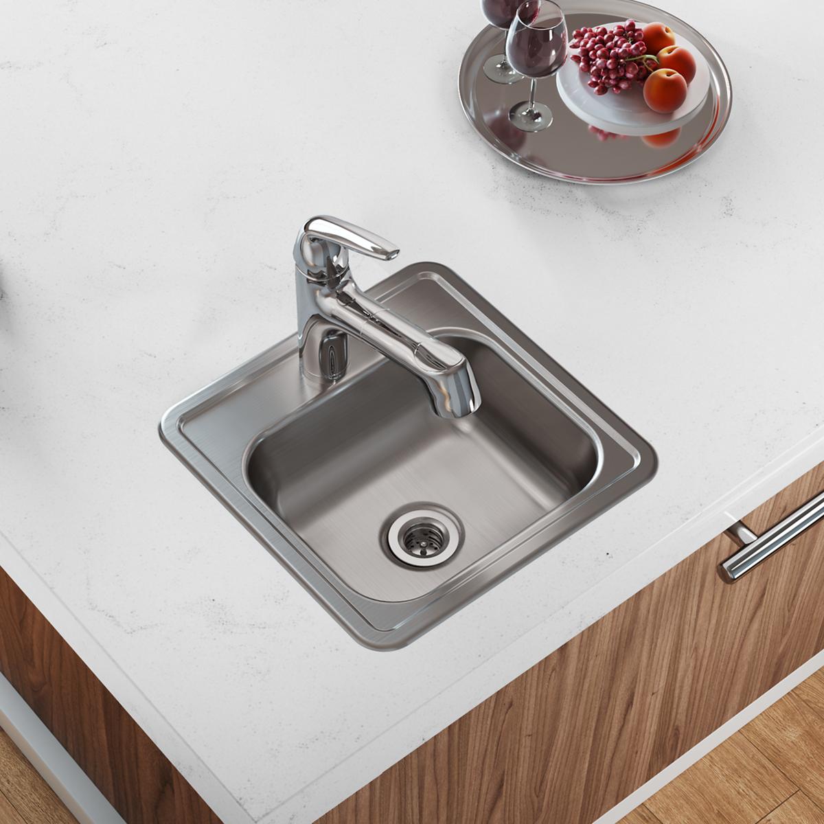 Stainless steel drop-in bar sink with single bowl, faucet, and drain opening installed in white countertop.