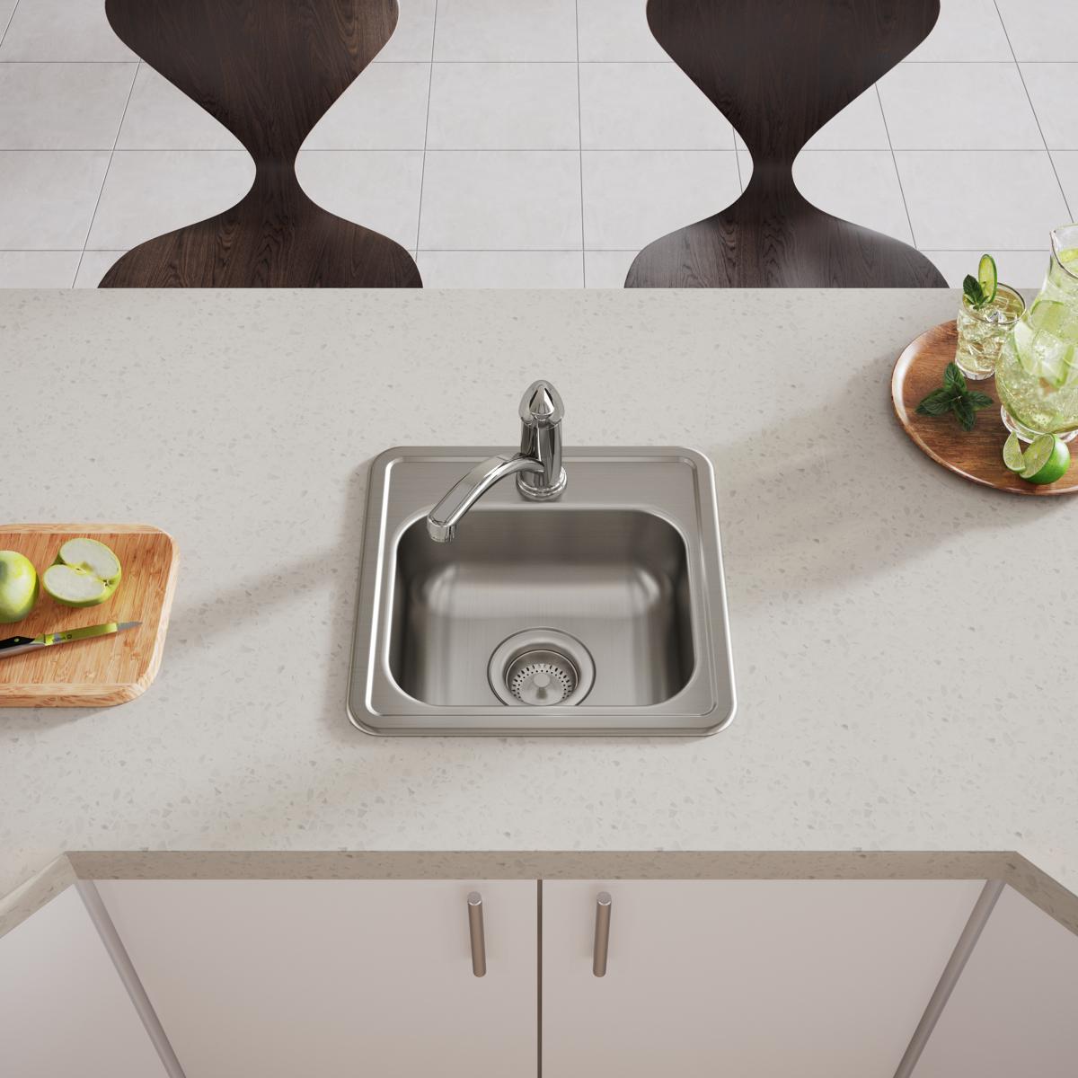 Stainless steel drop-in bar sink with single bowl, faucet hole, and drain strainer installed in light countertop.