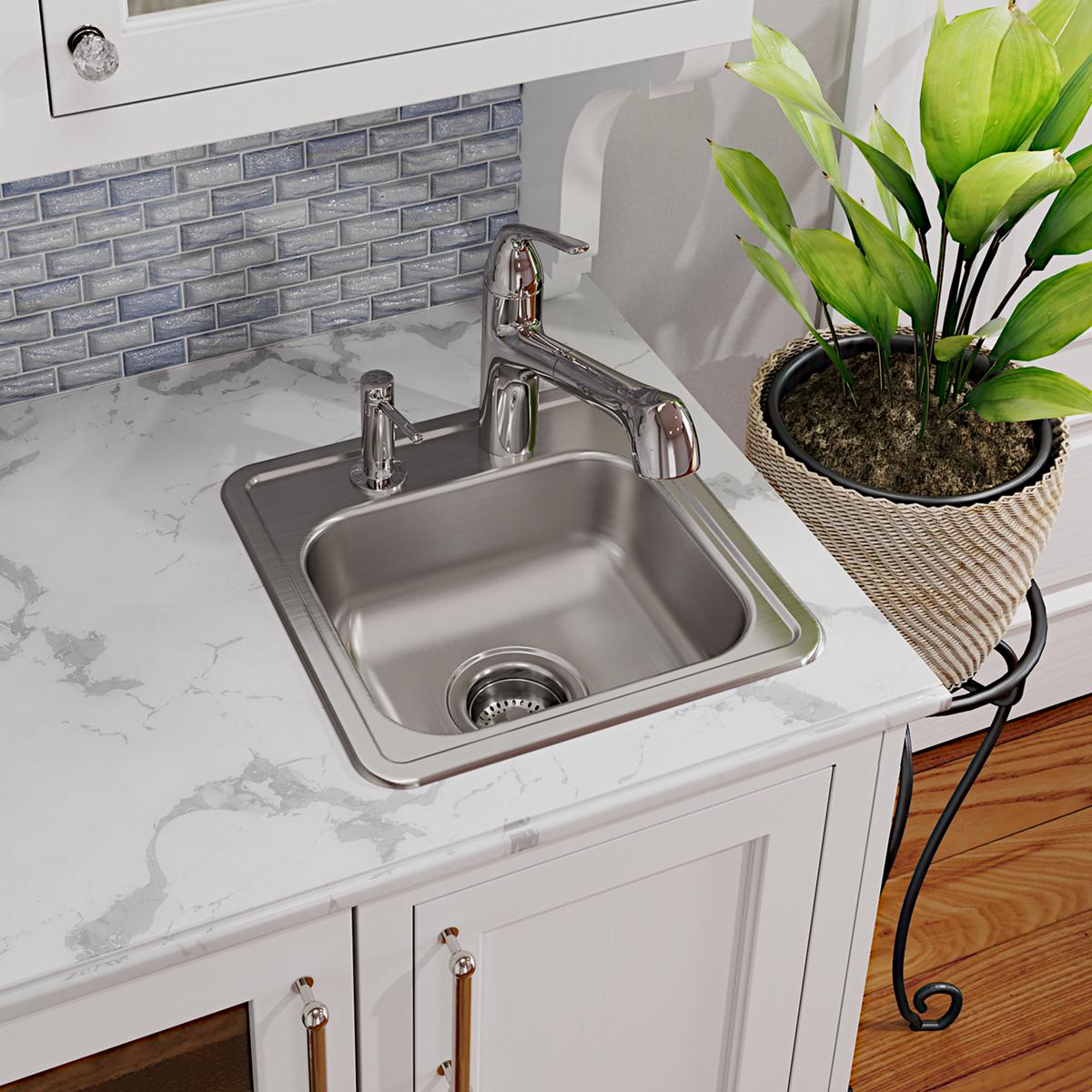 Stainless steel drop-in bar sink with single bowl, chrome faucet, and drain strainer installed in white countertop.