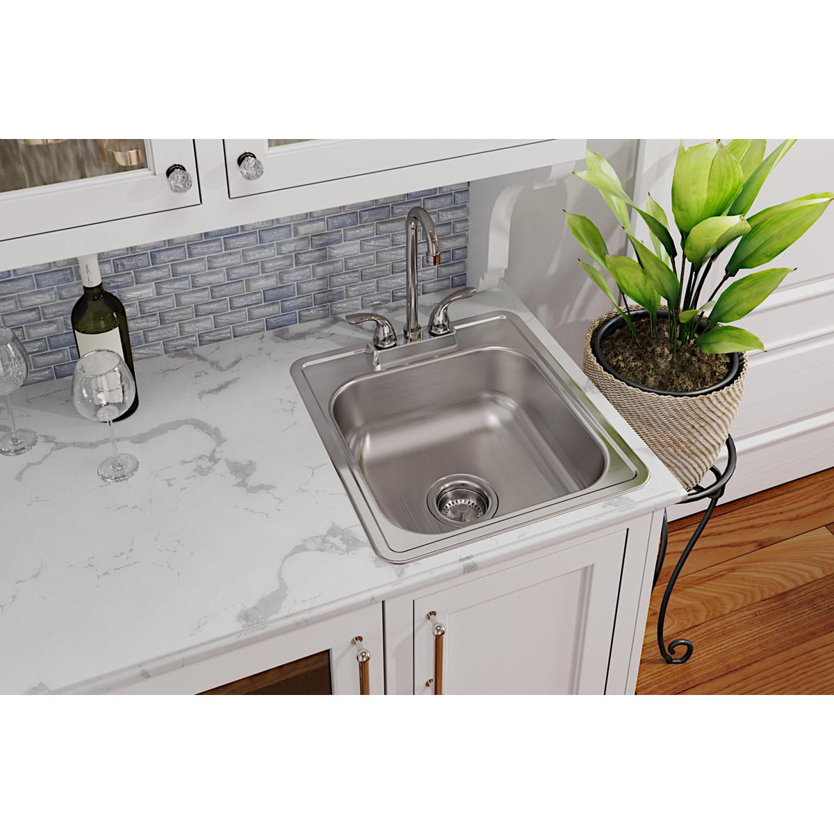 Stainless steel single bowl drop-in bar sink installed in white countertop with chrome faucet and drain.