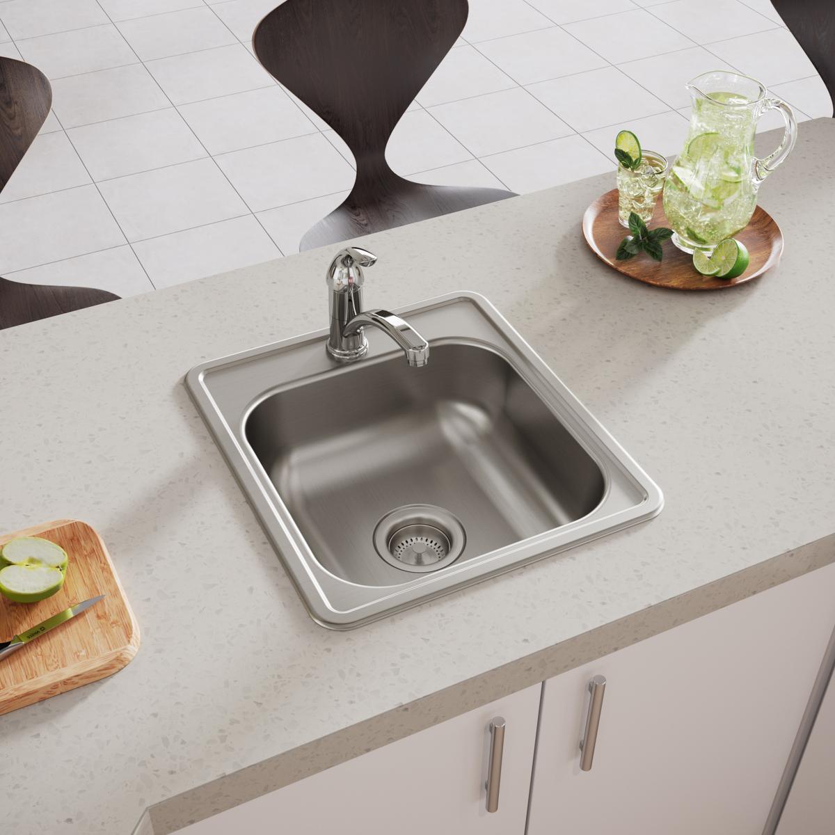 Stainless steel drop-in bar sink with single bowl and faucet mounted in light countertop, single drain hole visible.