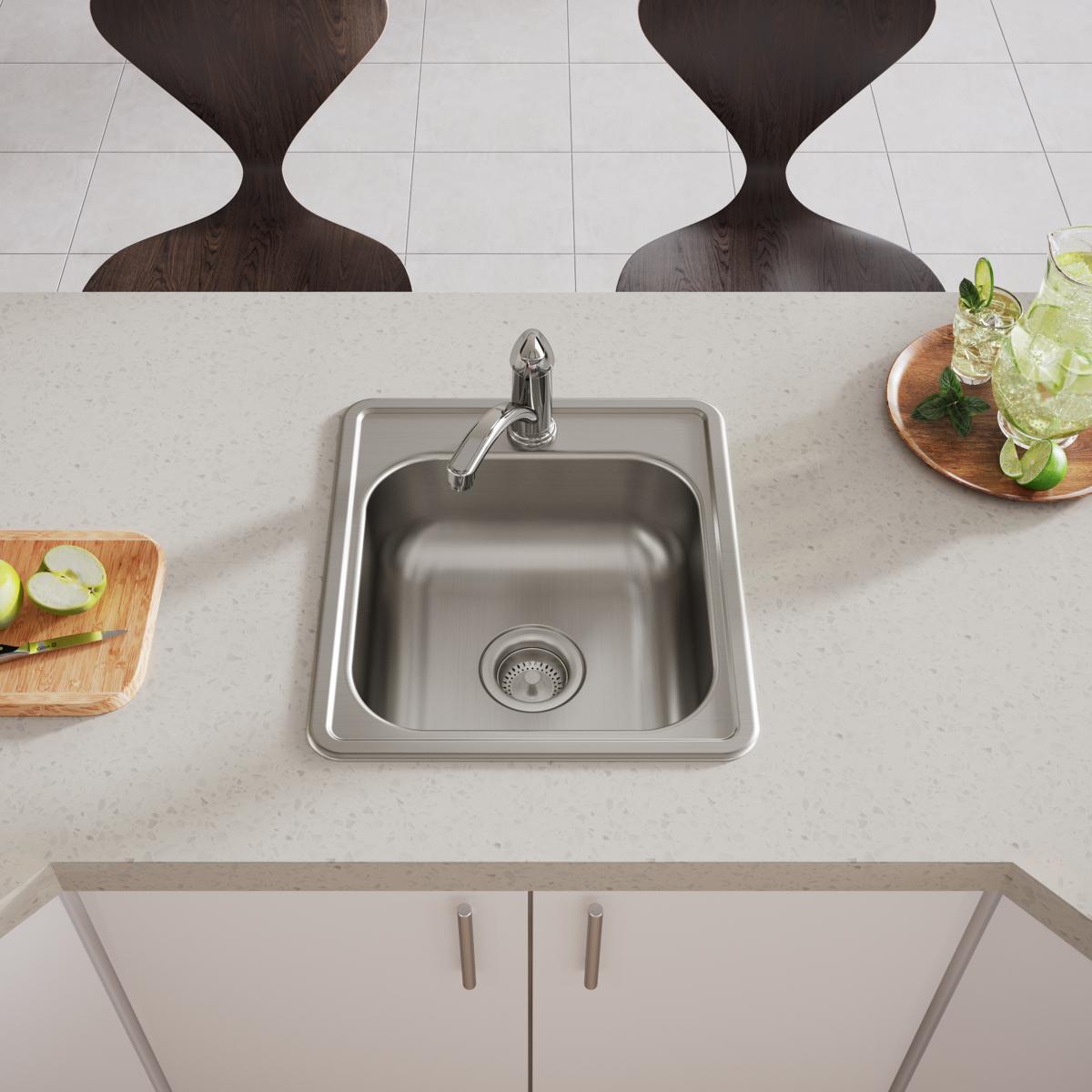 Stainless steel drop-in bar sink with single bowl, drain strainer, and faucet mounted in light countertop.