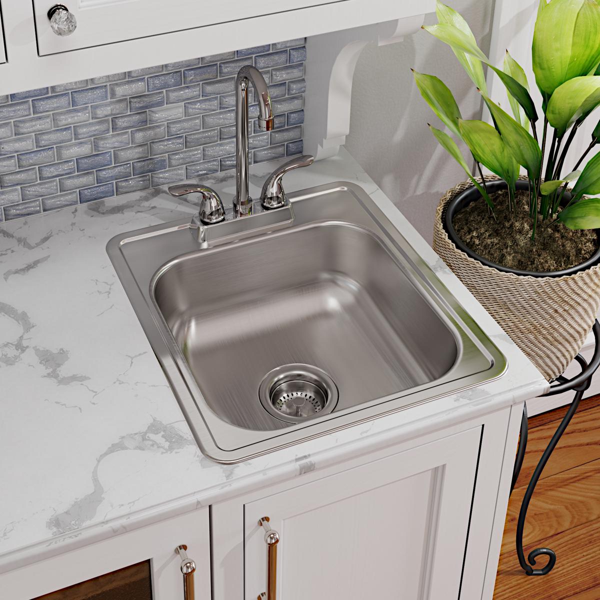 Stainless steel drop-in bar sink with single bowl, drain strainer, and chrome faucet installed in white countertop.