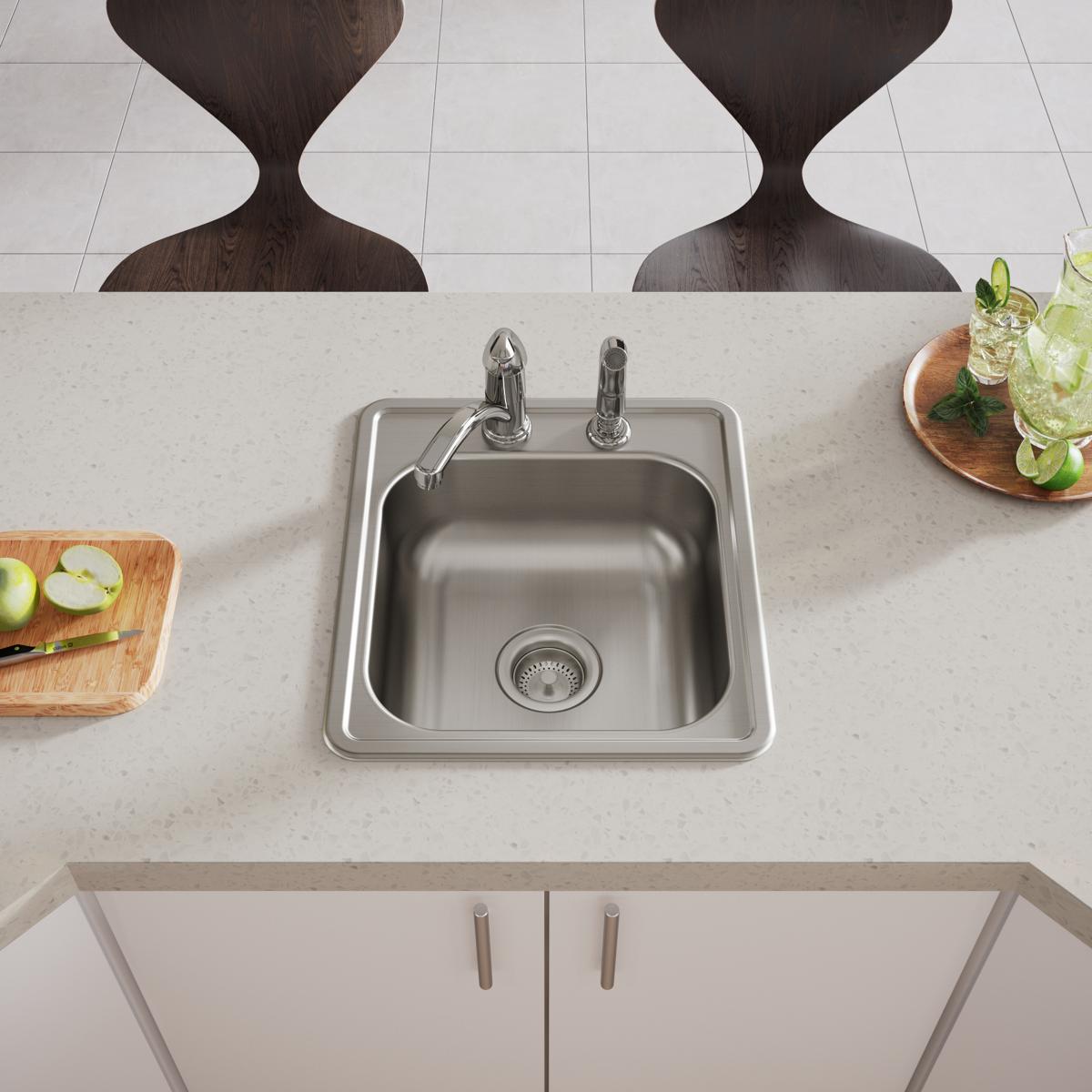 Stainless steel drop-in bar sink with single bowl, two faucet holes, and drain strainer installed in countertop.