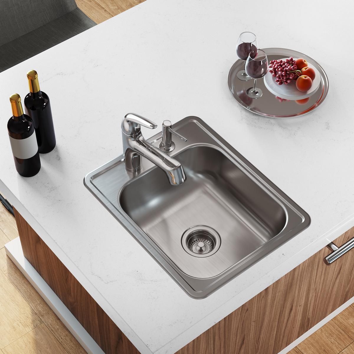 Stainless steel drop-in bar sink with single bowl, drain strainer, and faucet mounted on white countertop next to wine bottle