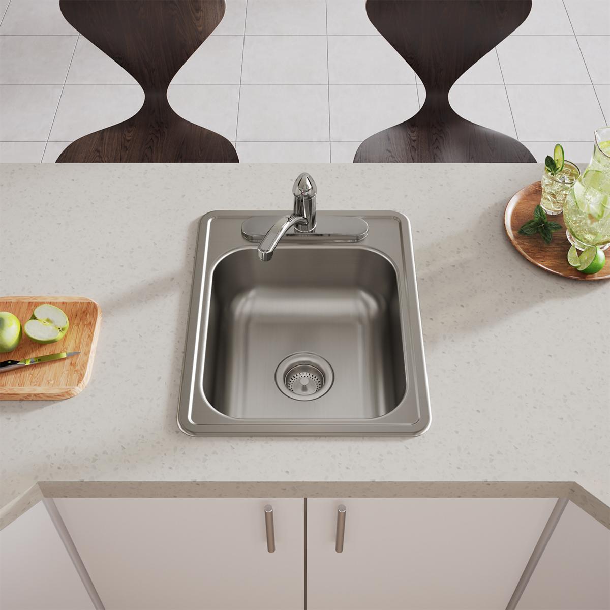 Stainless steel drop-in bar sink with single bowl, faucet, and drain strainer installed in white countertop.