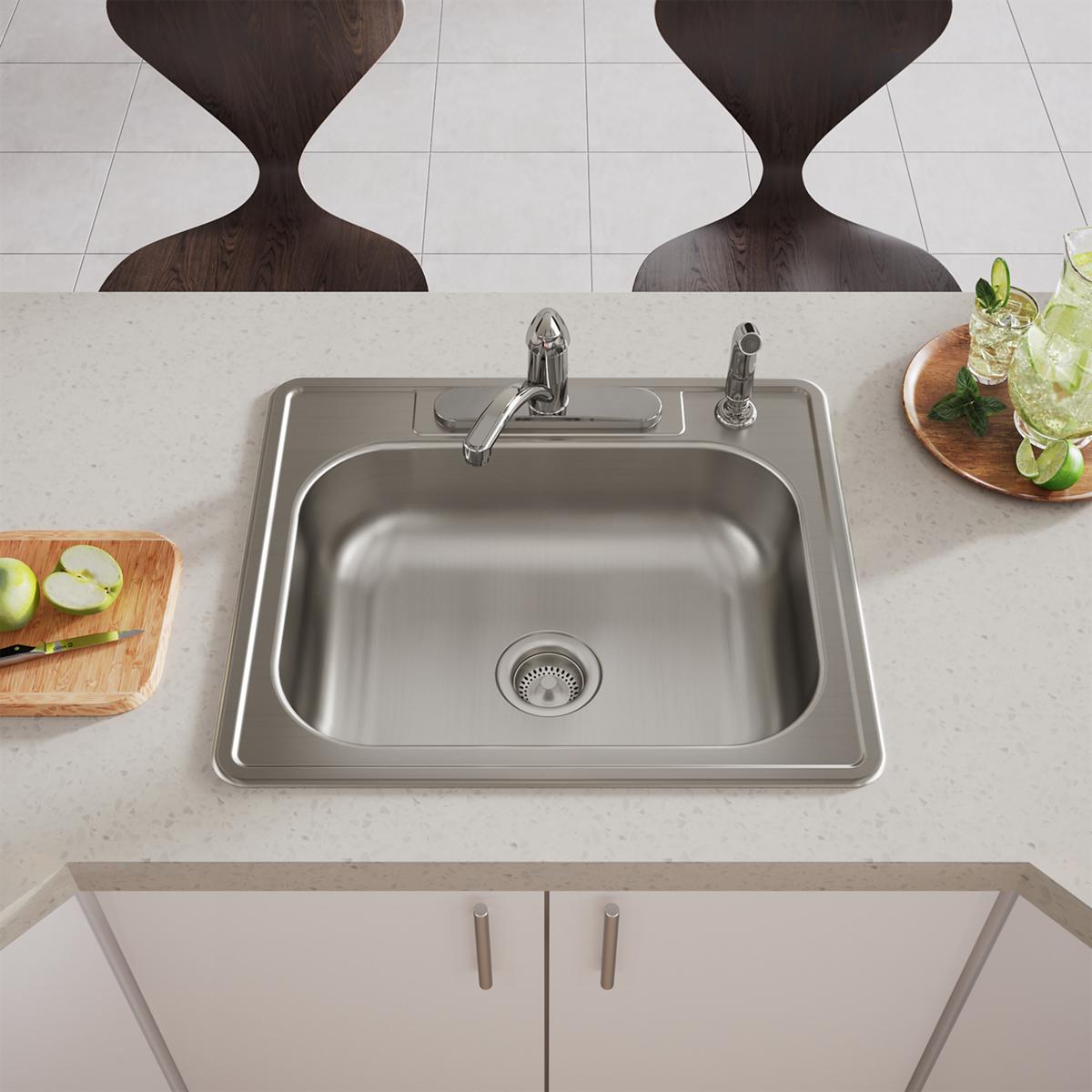 Stainless steel drop-in sink with single bowl, two faucet holes, and drain strainer installed in light countertop.