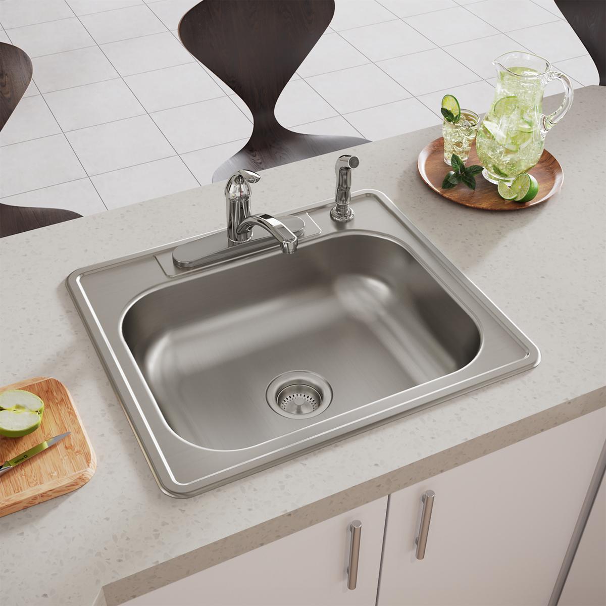 Stainless steel drop-in sink with single bowl, chrome faucet, and four holes installed in light countertop.