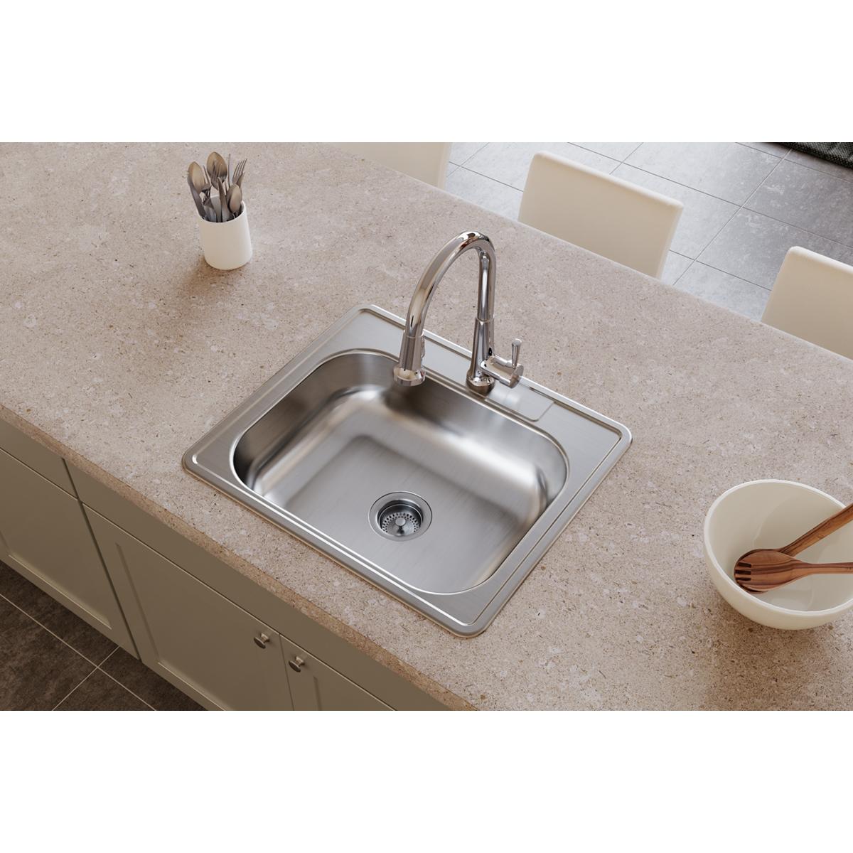 Stainless steel single bowl drop-in sink with chrome faucet installed in beige countertop.
