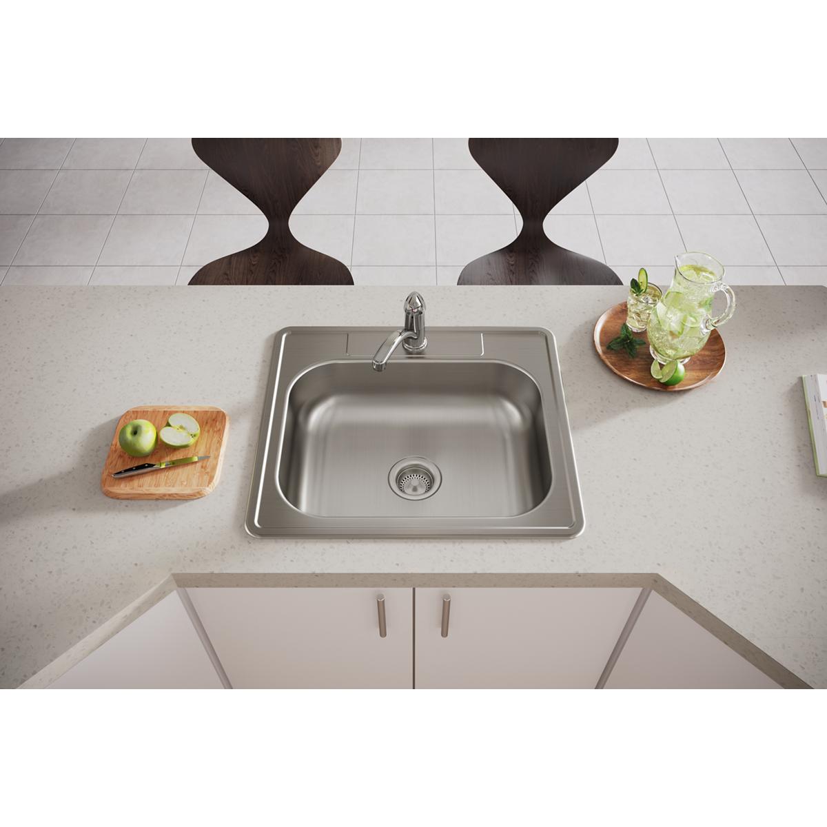 Stainless steel single bowl drop-in sink with faucet hole, installed in light countertop with wooden chairs and place setting