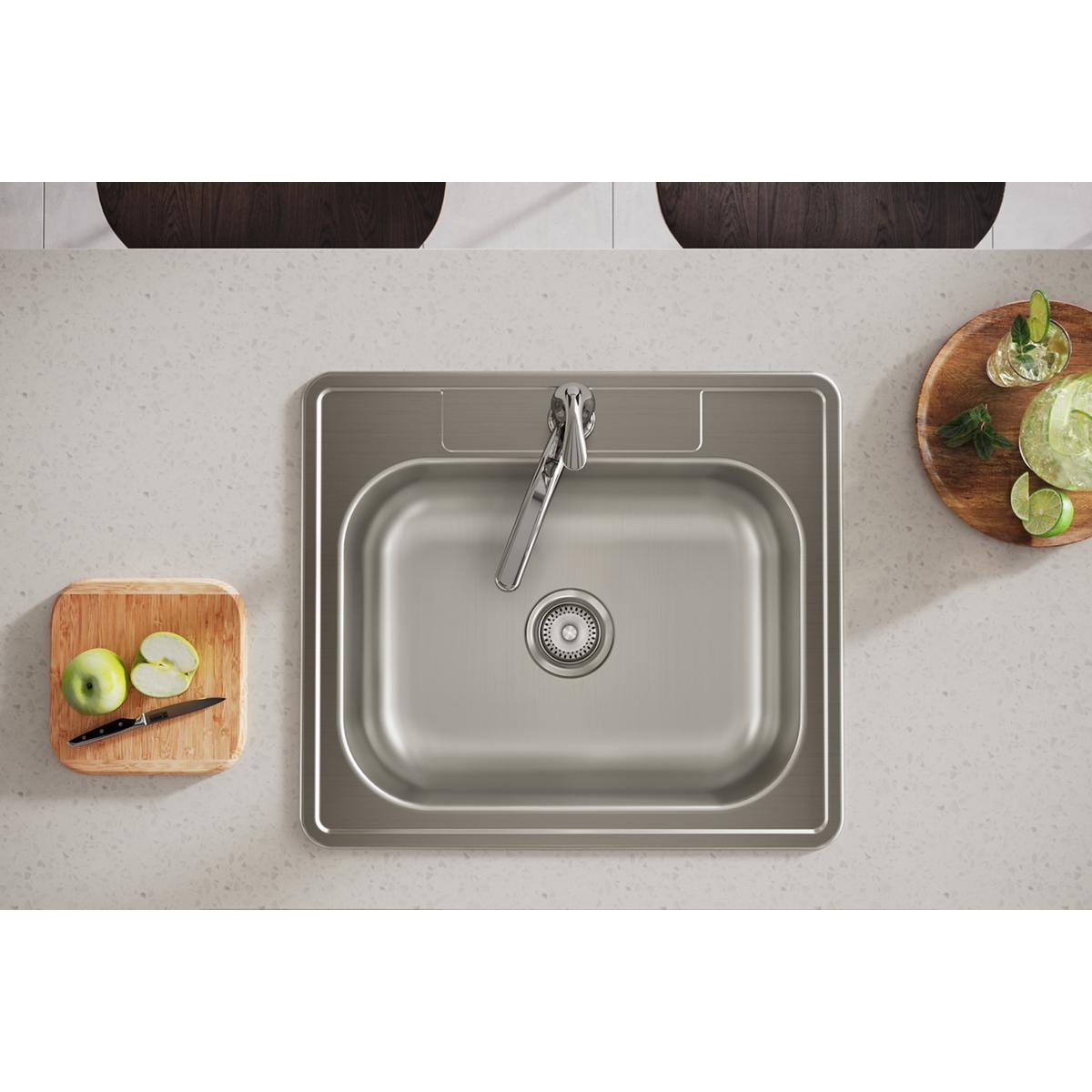 Stainless steel single bowl drop-in sink with one faucet hole, installed in light countertop with wooden cutting boards nearb