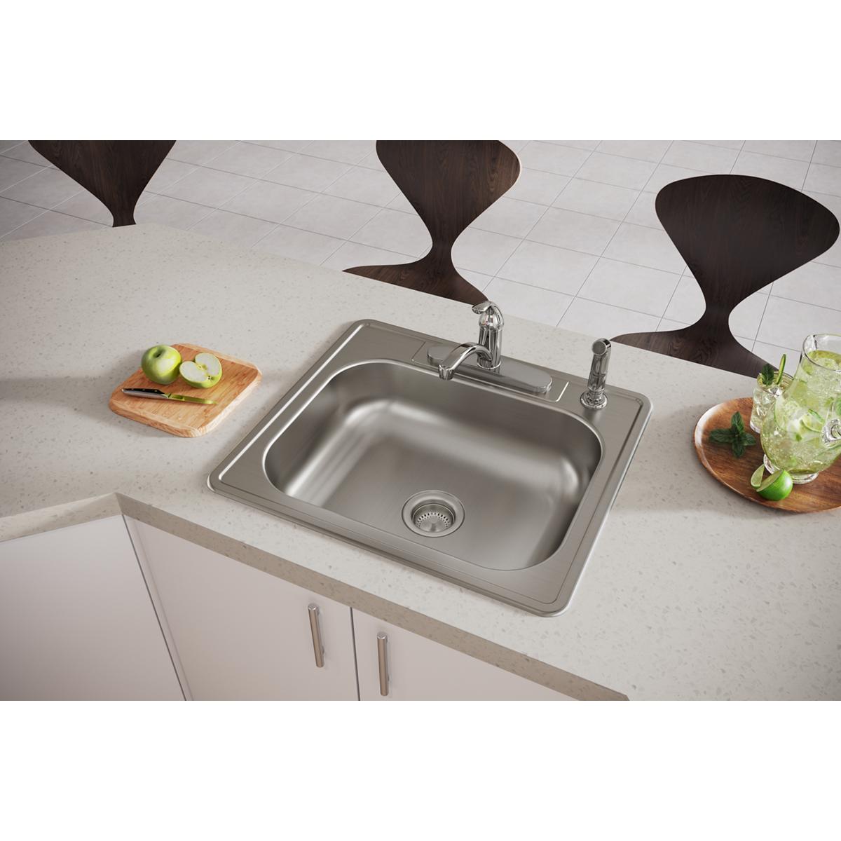Stainless steel drop-in sink with single bowl and four mounting holes installed in white countertop with faucet and drain.