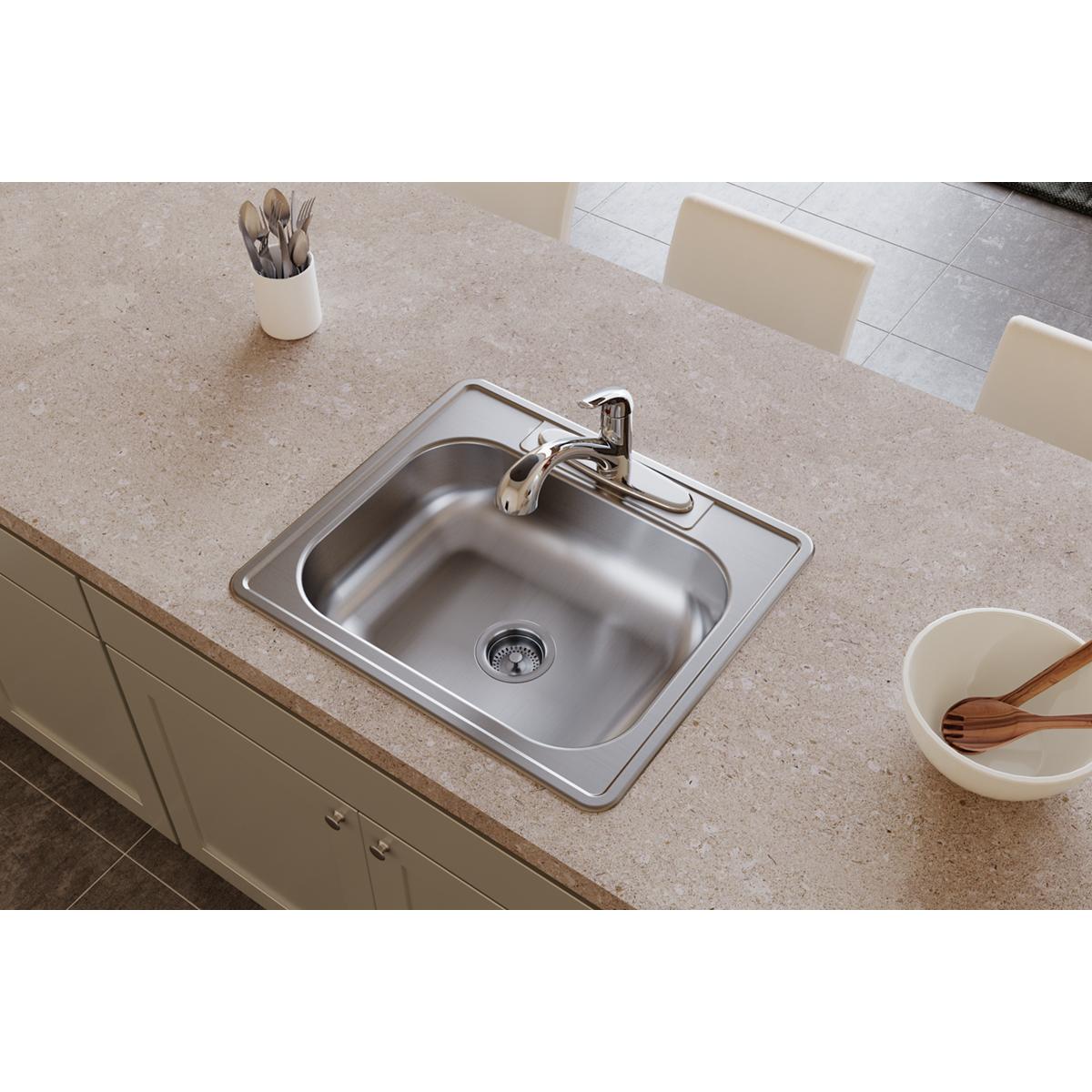 Stainless steel single bowl drop-in sink with faucet and drain installed in countertop.
