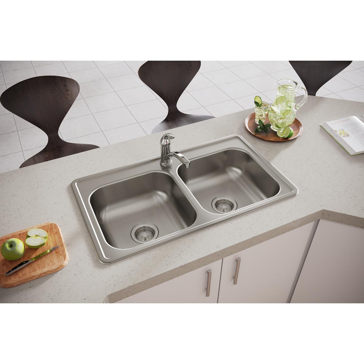 Stainless steel double bowl drop-in sink with single faucet hole installed in light countertop next to cutting board and beve