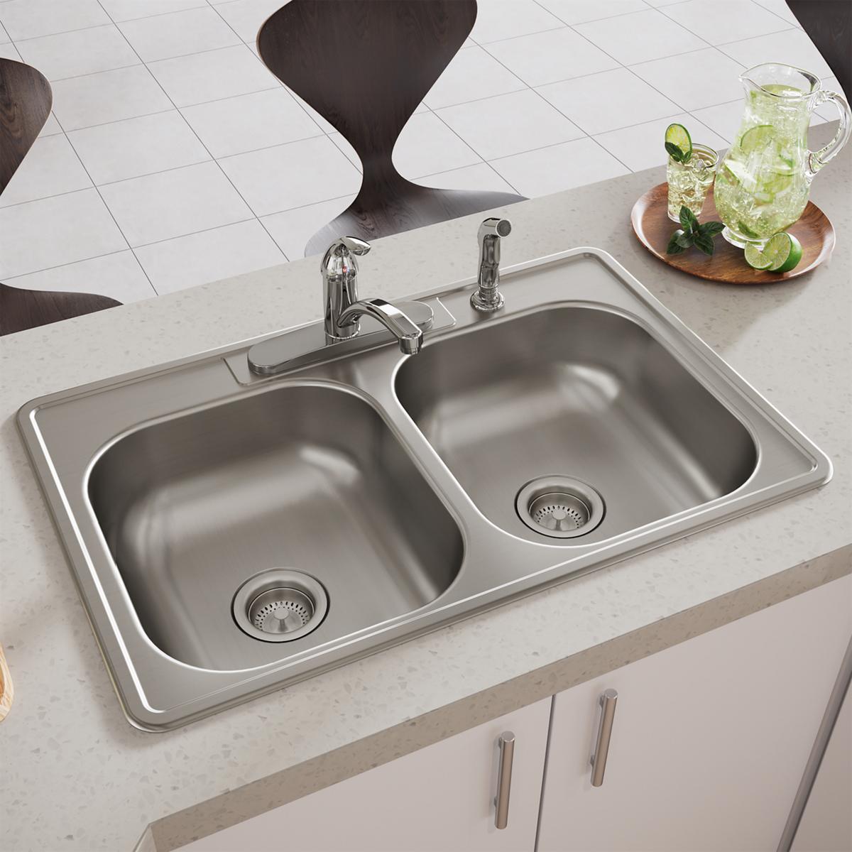 Stainless steel double bowl drop-in sink with two equal-sized basins, drain strainers, and chrome faucet mounted on light cou
